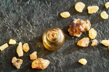 Bir şişe aromaterapi koyu arkaplanda tütsü reçinesi olan gerekli yağ.