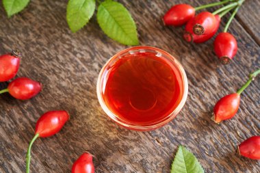 Cam bir kase gül tohumu yağı ve taze yapraklar.