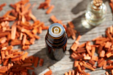 Masada kırmızı sandal ağacı parçacıkları olan koyu renkli bir aromaterapi şişesi.