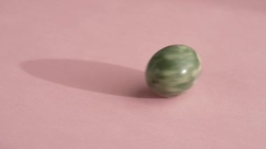 Yeşil yeşim yumurta pembe arka planda dönüyor, yavaş çekim.