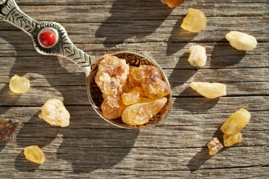 Tütsü reçinesi parçaları ahşap bir masada kaşığın üzerinde, en üstte.