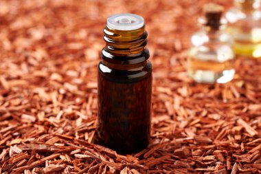 Koyu bir şişe aromaterapi kırmızı sandal ağacı parçacıkları ile gerekli yağ