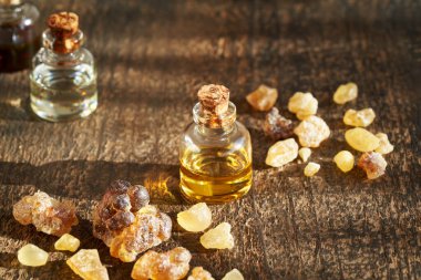 Ahşap arka planda tütsü reçinesi kristalleri olan bir şişe aromaterapi.