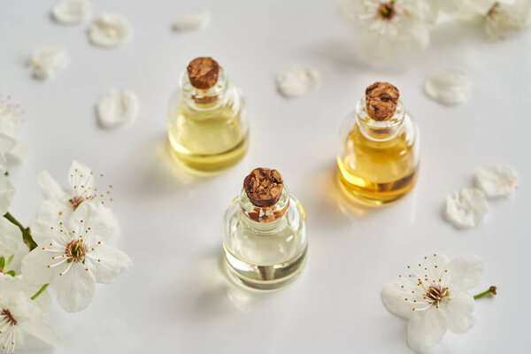 Бутылки ароматерапии эфирное масло с белыми цветами весной на белом фоне