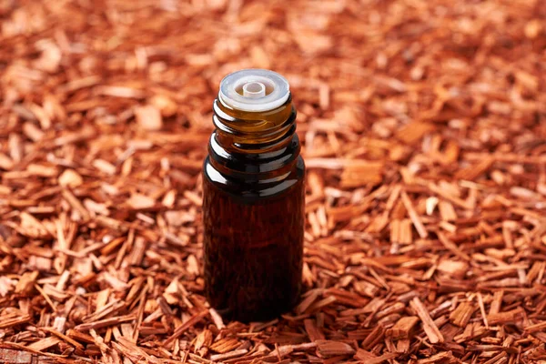A dropper bottle of aromatherapy essential oil with red sandalwood chips, with copy space