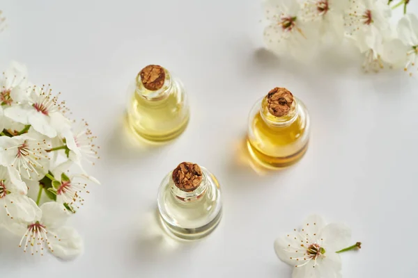 Ätherische Ölflaschen Mit Weiß Blühenden Ästen Frühling Auf Weißem Hintergrund — Stockfoto