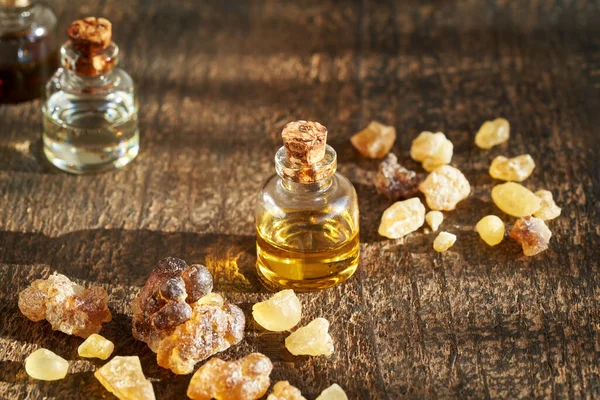Ahşap arka planda tütsü reçinesi kristalleri olan bir şişe aromaterapi.