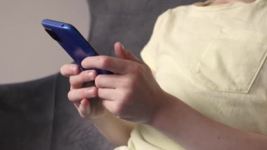 Elinde mavi bir cep telefonu tutan ve oyun oynayan bir çocuk.