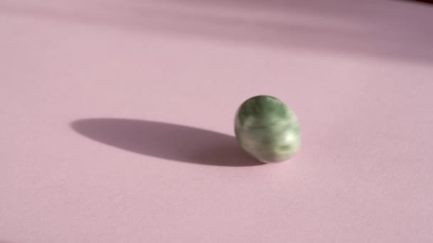 Green Jade Egg Spinning Pastel Pink Background Slow Motion — Stock Video