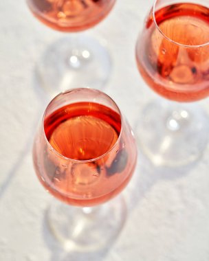 Parlak bir arka planda üç bardak gül şarabı.