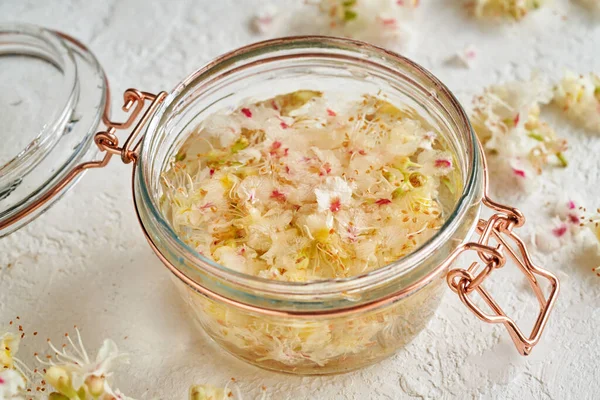 Bitkisel tentürü hazırlamak için at kestanesi çiçeği ve alkol dolu cam bir kavanoz.