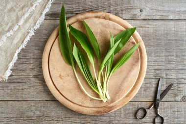 Tahta bir masanın üstünde taze, vahşi sarımsak yaprakları.