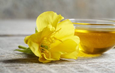 Taze akşam çiçekleri ve arka planda bir kase yağ.