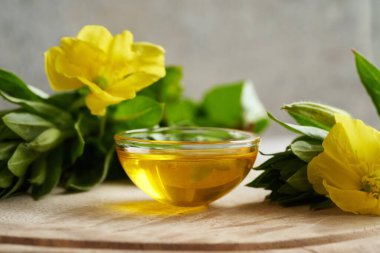 Bir kase çuha çiçeği yağı ve ahşap bir masada taze çiçek.