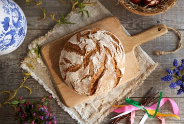 Paskalya dekorasyonu ve bahar çiçekleriyle ev yapımı ekşi ekmek.