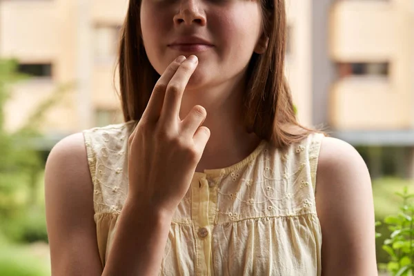 Young teenage girl practicing EFT or emotional freedom technique outdoors - tapping on the chin point