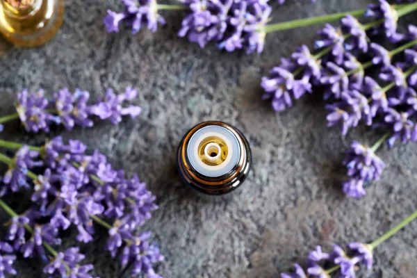 A dropper bottle of aromatherapy essential oil with fresh lavender flowers, top view