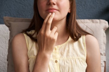 Hand of a girl practicing EFT or emotional freedom technique - tapping under the mouth