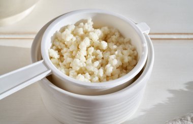 Fresh milk kefir grains in a strainer on white background - source of probiotics