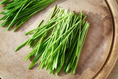 Fresh green barley grass blades on a wooden cutting board, top view