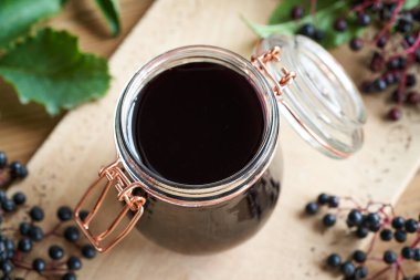 Arka planda taze olgun böğürtlenli ev yapımı siyah yaşlı şurubu.