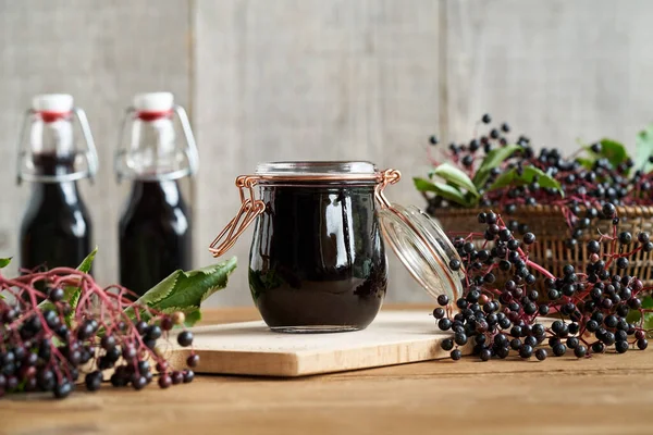 Black elder syrup with fresh elderberries on a table. Herbal or alternative medicine.