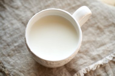 Masadaki beyaz bardakta taze süt kefir.