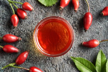 Bir kase gül tohumu yağı ve taze böğürtlen ve yapraklar.