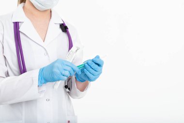 Maskeli genç bir hemşire beyaz önlüklü beyaz arka planda bir şırınga açar. Aşı yapmak için, iğne yapmak için. Aşılama ve gribe karşı koruma kavramı, hırslı, kopyalama alanından