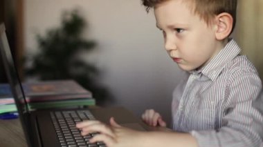 Avrupalı bir çocuk dizüstü bilgisayarda yazmayı öğreniyor. Online okul. Uzaklık öğrenimi.