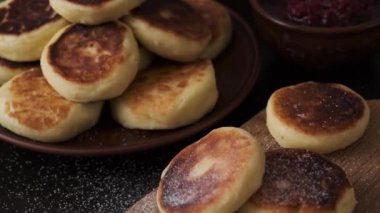 Süzme peynirden yapılmış peynirli kekler ahşap bir tahtada, çömlekçilikte, karanlık bir masada. Ev yapımı süzme peynirli hamur işleri. Tüm aile için protein kahvaltısı..