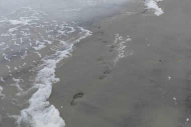 Kumsalda yalın ayak izleri, su ve deniz köpüğü, yolculuk ve yol daha az seyahat edilmiş görüntü, yatay görünüm