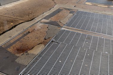 Kaldırımın yüzeyi, çoklu yamalı alanlar ve metal ızgaralar, yatay görünüm