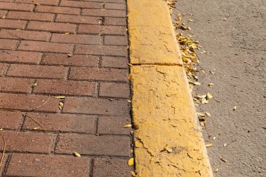 Beton kaldırımda kırmızı tuğlalı kaldırım parlak sarı, çamurlu asfalt yol yatağı, yatay görünüm