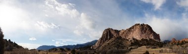 Panorama of a massive rock outcropping before a ridge of the Rocky Mountains, Colorado American west with dramatic clouds, horizontal aspect clipart
