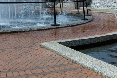 Halka açık bir çeşme alanındaki su akıntılarının etrafındaki tuğla yürüyüş yolu, yatay görünüm