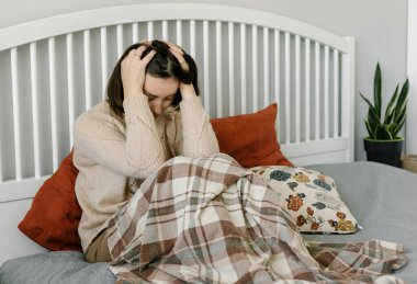 Evde yatağında oturan bitkin, bitkin bir kadın. Akıl sağlığı konsepti. Coronavirus covid-19 hastalığının sonuçları.