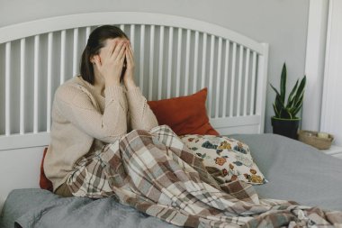 Evde yatağında oturan bitkin, bitkin bir kadın. Akıl sağlığı kavramı. Coronavirus covid-19 hastalığının sonuçları.