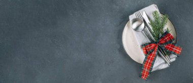 Yeni yıl için çatal bıçak ve süslemelerle süslenmiş afiş masası. Üst manzara, düz yatış. Web sayfası ve tasarım için uzun pankart