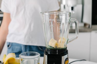 Kadın taze ev yapımı smoothie yapmak için karıştırıcıya ham malzeme koyuyor. Yakın plan.