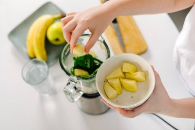 Blender ile yeşil detoks smoothie hazırlama işlemi. Vejetaryen bahar içkileri. Dikkatli yemek yeme, diyet yapma kavramı. Üst görünüm