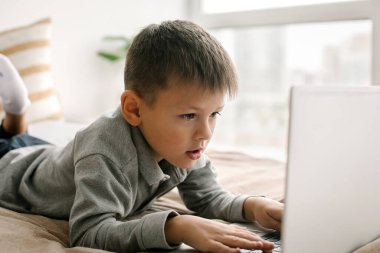 6-7 yaşındaki çocuk eğitim için dizüstü bilgisayar kullanıyor. Çevrimiçi eğitim kavramı, evde eğitim