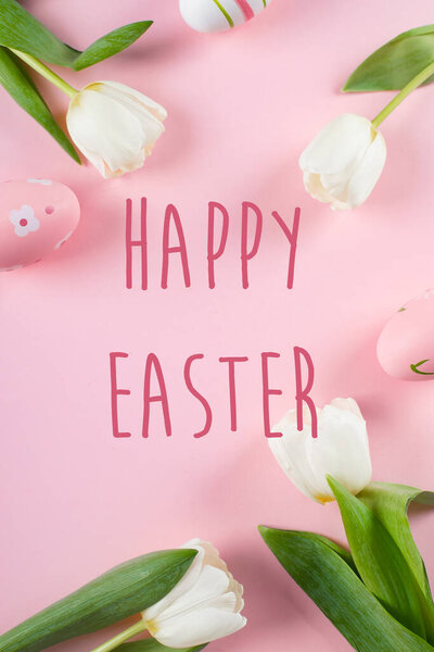 Happy Easter text on greeting card. Easter holiday concept. Tulips and easter eggs. Flat lay, top view
