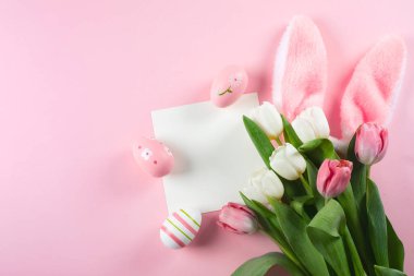 Paskalya yumurtaları, tüylü tavşan kulakları laleler ve mesaj için boş bir kart. Üst görünüm, düz görünüm, kopyalama alanı