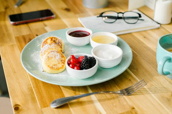 Sağlıklı yaz kahvaltısı. Taze böğürtlenli süzme peynir krepleri ve ahşap masada kapuçino kahvesi. Yakın plan.