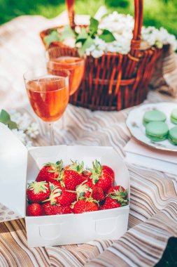 Yaz pikniği. Taze çilekli kutu, şarap, tatlı kurabiyeleri, leylak çiçekli sepet. Yakın çekim.