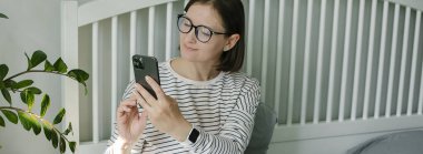 Güzel, genç bir kadın telefonuyla fotoğraf çekiyor. Video görüşmesi yapıyor. Uzak çalışma ve eğitim. Bağımsız kavram