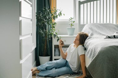 Telefonu elinde tutan liseli kız, arkadaşlarıyla sohbet etmek için cep telefonu kullanıyor..