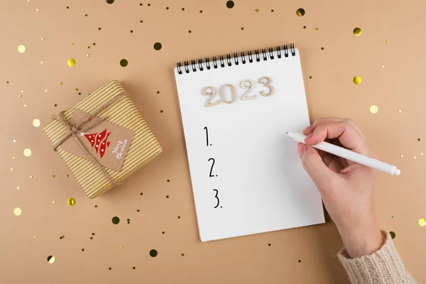Concept of Goals 2023 and planning new year. Woman writing in note pad goals. Copy space, flat lay, top view.