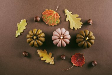 Balkabağı şeklinde yanan mum, arka planda sonbahar yaprakları. Sonbahar, Cadılar Bayramı, Şükran Günü konsepti. Düz konum, üst görünüm, kopyalama alanı